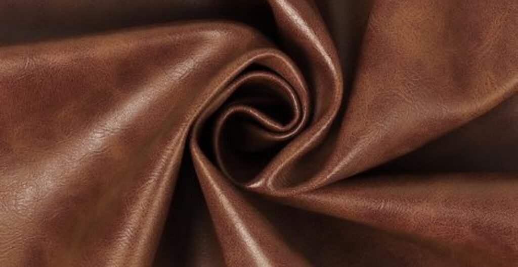 Close-up of textured brown microfiber leather fabric arranged in a spiral.
