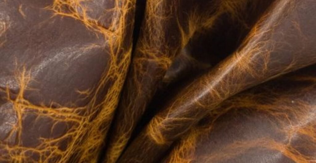 pull up leather with a distressed, crackled texture. Close-up of folded pull up leather with gold veining.