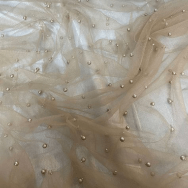 Close-up of sheer tulle fabric in a nude color, adorned with small decorative beads.