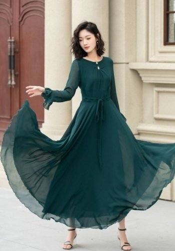 Model in a dark green chiffon dress with long sleeves and a ruffled hem, twirling gracefully.