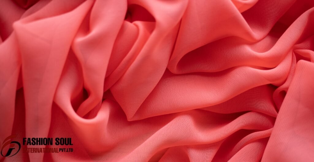 A close-up view of soft, coral chiffon fabric with flowing folds and a sheer texture. Smart & safely
