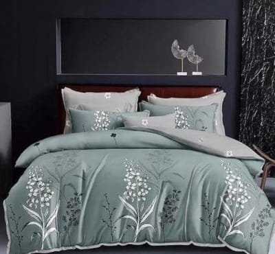 Bedding set in green with white floral designs on a dark wall background.