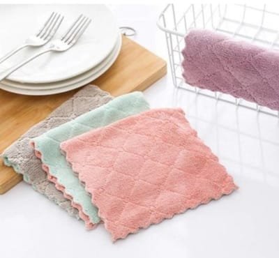 A set of pastel-colored, textured dishcloths arranged on a white kitchen countertop with a stack of white plates, forks, a wooden cutting board, and a wire dish rack in the background. Indirect Uses of Cotton You Encounter Every Single Day Indirect Uses of Cotton 
