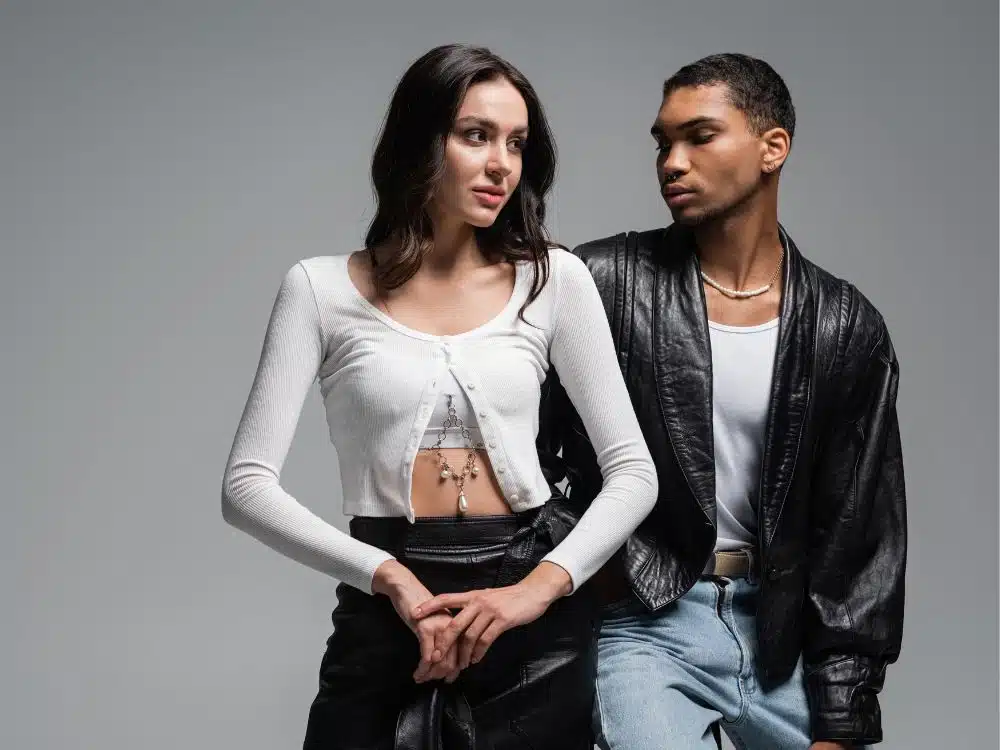 Fashionable couple posing together in trendy outfits against a neutral background.