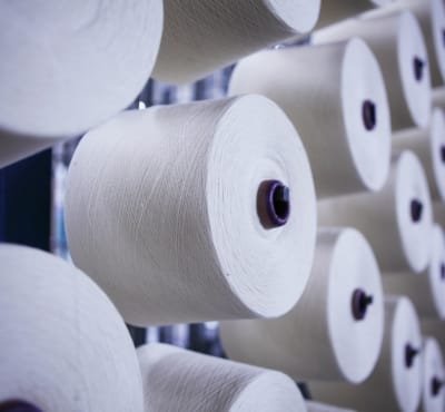 Rolls of cotton yarn stacked in a textile factory.