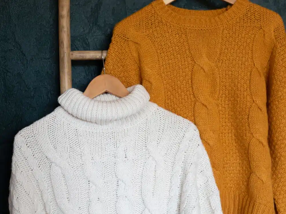 Cozy knitted sweaters hanging on a rack in warm colors.