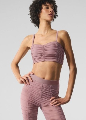 Model wearing a mauve-colored, ruched two-piece outfit consisting of a cropped top and high-waisted leggings.
