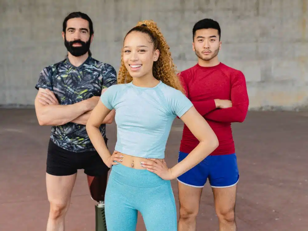 Diverse group of three athletes posing confidently in a gym setting.