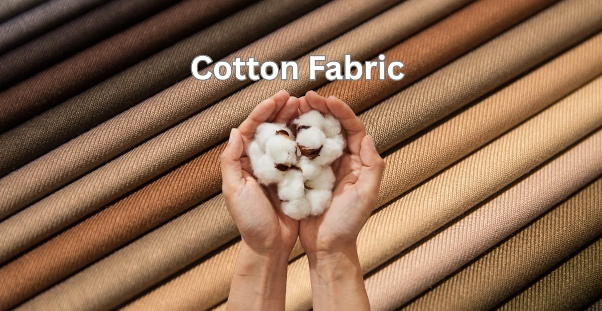 A pair of hands holding cotton bolls in front of textured high quality cotton fabric in various neutral shades.