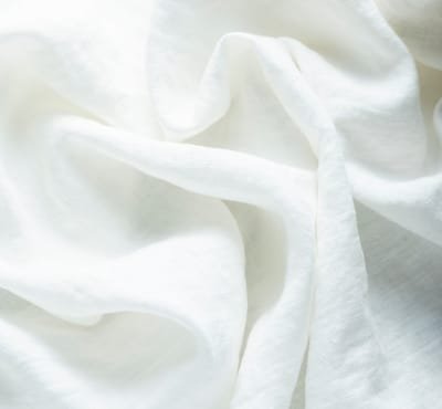 Close-up of white linen fabric, showcasing its soft, textured appearance.