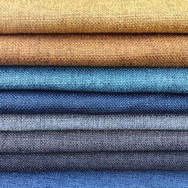 Stacked linon fabric in various colors, including shades of brown, teal, and blue.