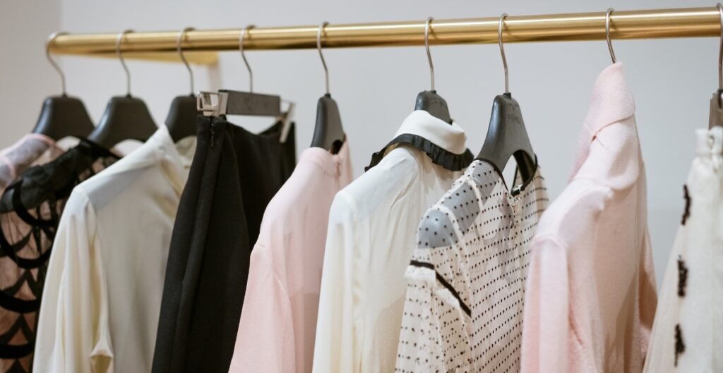 Clothing items neatly displayed on a gold rack, featuring blouses in various colors and patterns alongside black pants.