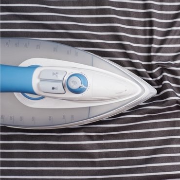 An overhead view of a steam iron resting on rayon fabric." how to iron rayon"