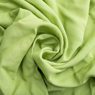 A close-up of soft, crumpled light green rayon fabric, showcasing its smooth texture and flow.