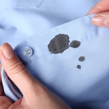A person holding a blue shirt with a paint stain on the sleeve." how to launder rayon"