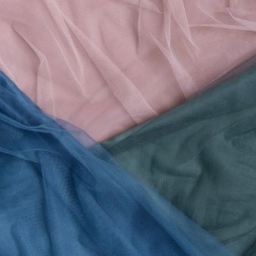 A flat lay of layered tulle fabric in pastel pink, soft green, and deep blue.