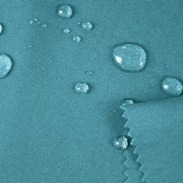 Close-up of water-resistant baize fabric showing droplets of water on its surface.