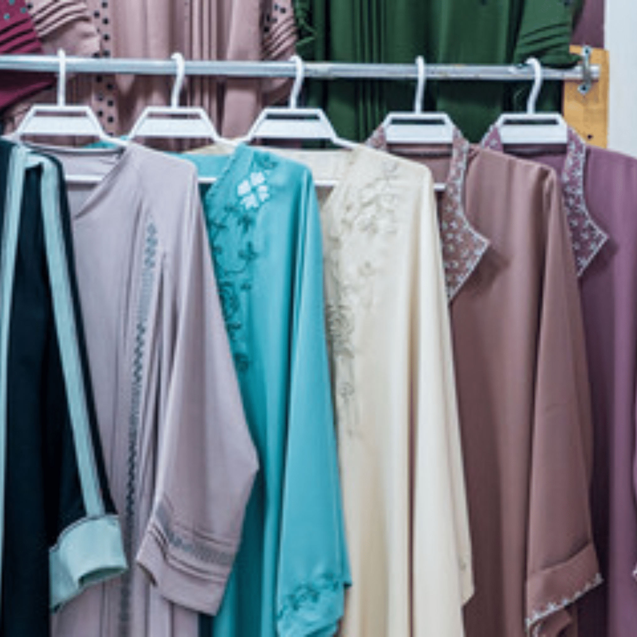 Colorful collection of wholesale abaya designs hanging on display rack.