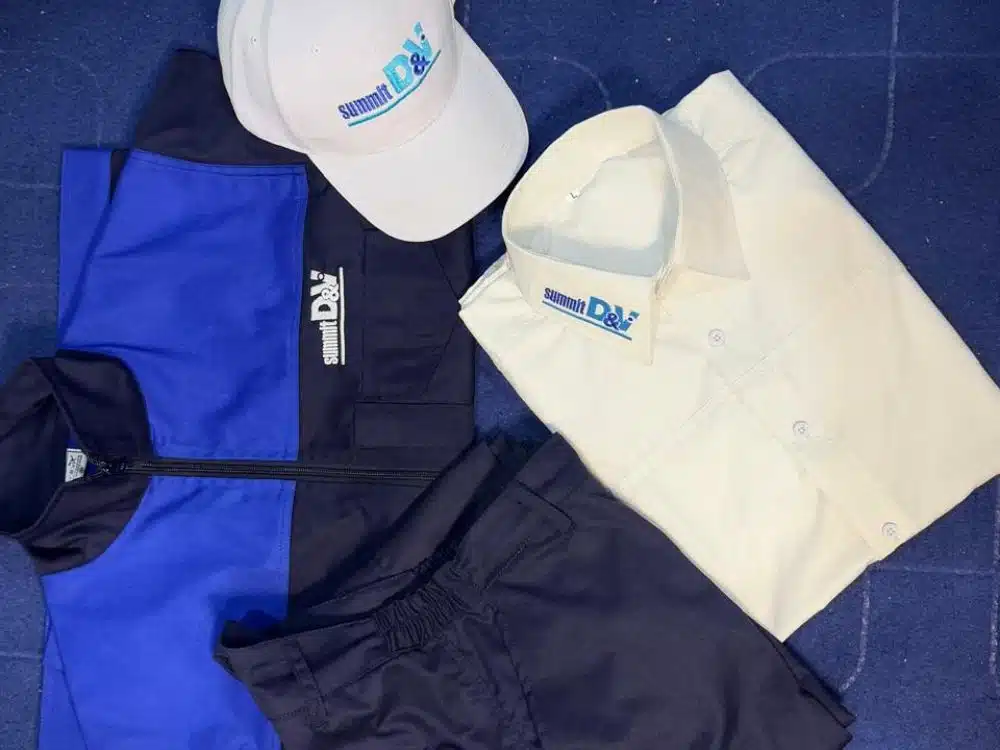 Collection of branded apparel including a jacket, shirt, cap, and pants neatly arranged on a surface.