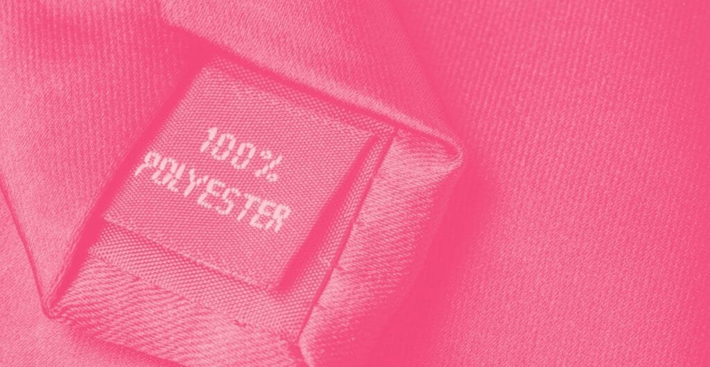 Close-up of a pink fabric label reading "HERSCHEL 100% POLYESTER" sewn onto a textured pink textile.
