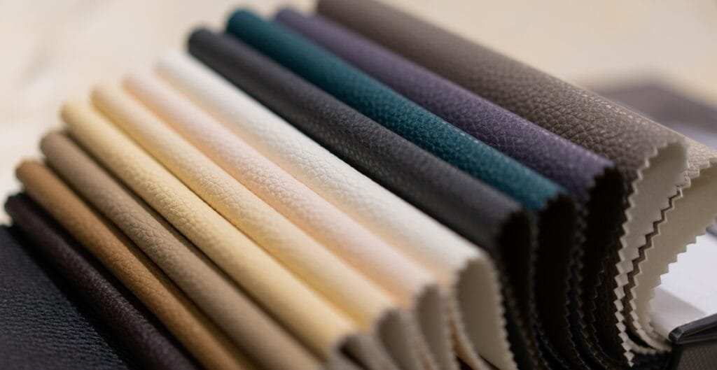A collection of fabric swatches in various colors and textures, fanned out on a surface.