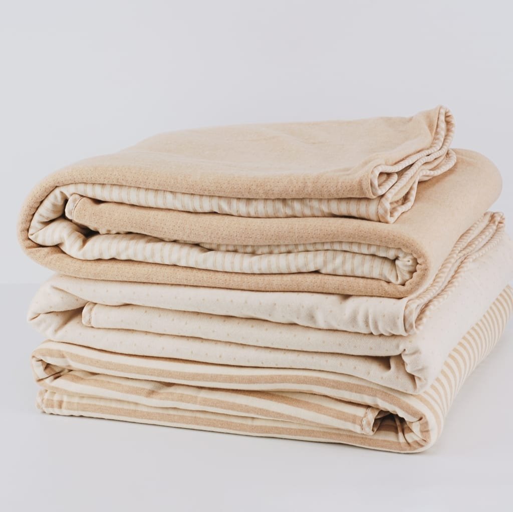 A neatly stacked pile of six beige and cream-colored cotton fabrics, folded uniformly.