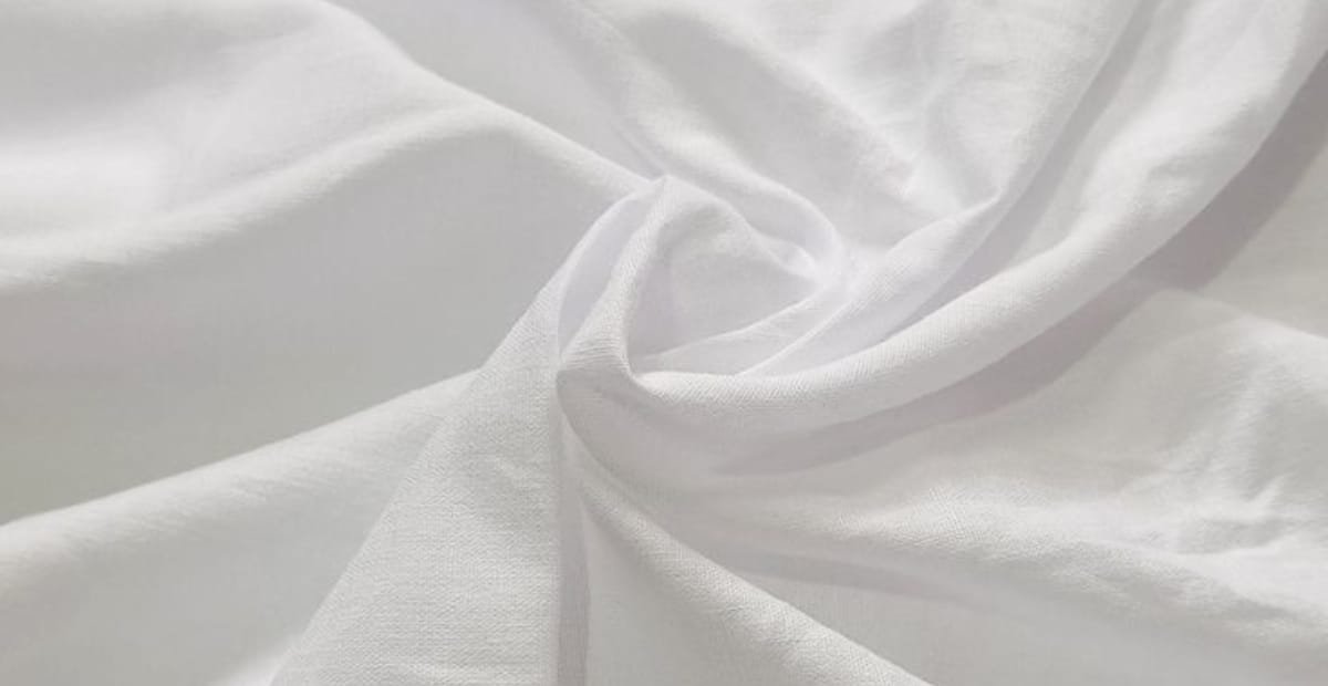 A close-up image of soft, white cotton fabric gently draped and twisted.