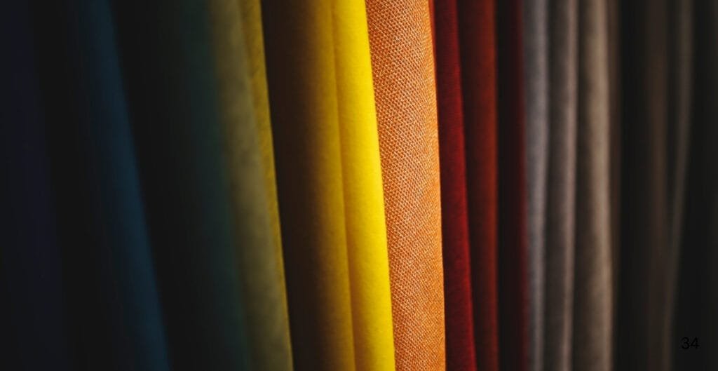 Close-up of vertically arranged colorful fabric swatches, primarily in shades of yellow, orange, red, and neutral tones.