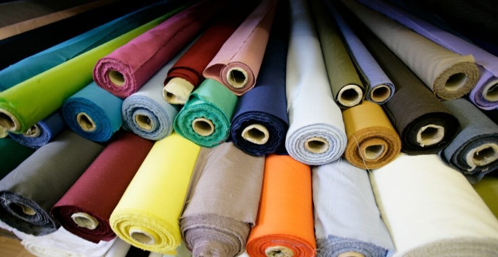 A variety of colorful rolls of cotton fabric neatly arranged on a table.