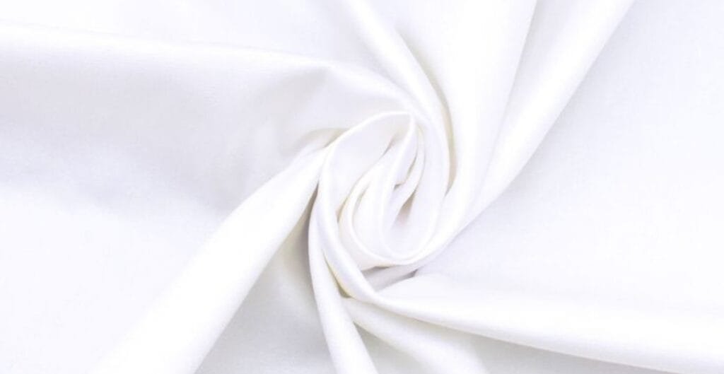Close-up of smooth, white cotton fabric gathered and twisted.