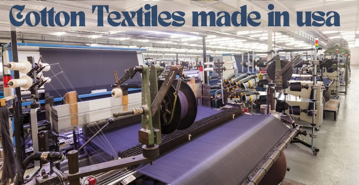 Interior view of a textile manufacturing plant with machinery producing cotton fabrics, with a large sign overhead that reads "Cotton Textiles made in USA.
