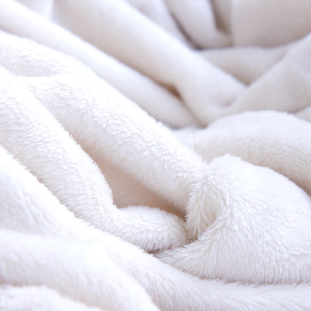 Close-up of soft, fluffy white cotton fabric with a plush, cozy appearance, draped in gentle folds.