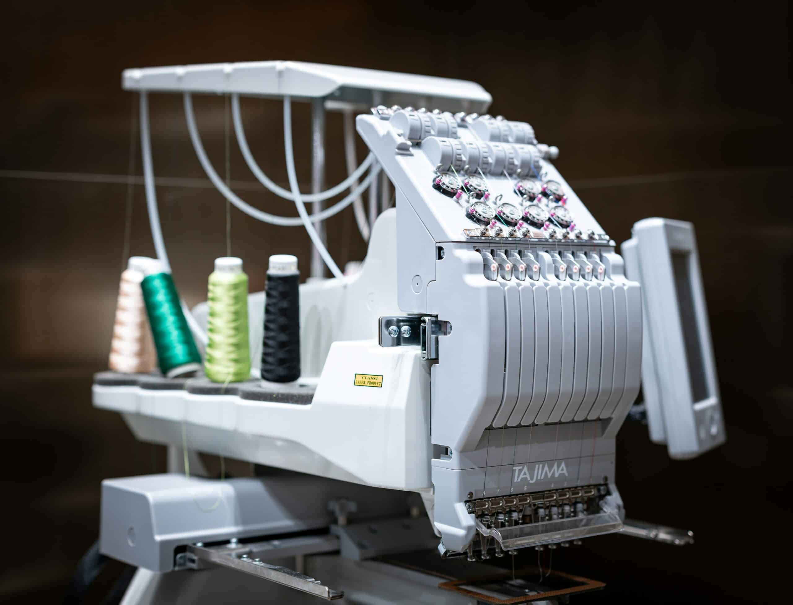 custom clothing manufacturer in Maryland. Sewing embroidery machine with spools of thread.