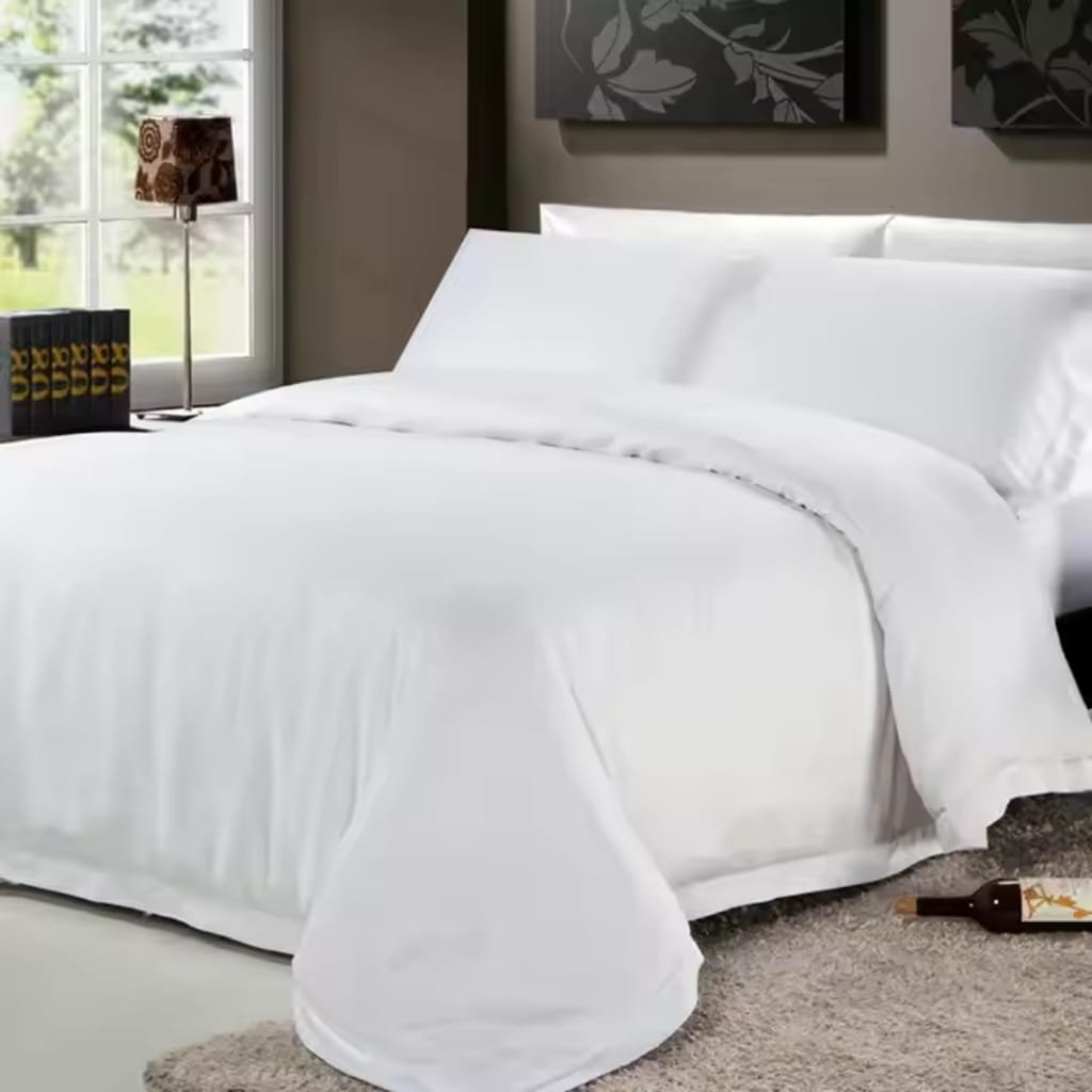 A neatly made bed with pristine white sheets and pillowcases, positioned next to a window with a view of greenery outside. On the side table, there are several black books with yellow text, and a decorative lamp with a floral pattern lampshade. A bottle of wine lies on the beige carpet near the foot of the bed.