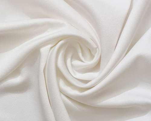 Close-up image of soft, white, silky fabric draped and twisted to showcase its smooth texture.