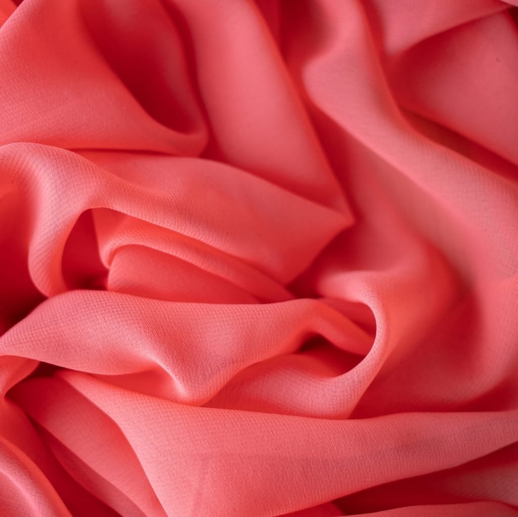 Close-up image of lightweight, soft, pink cotton fabric with gentle folds and smooth texture.