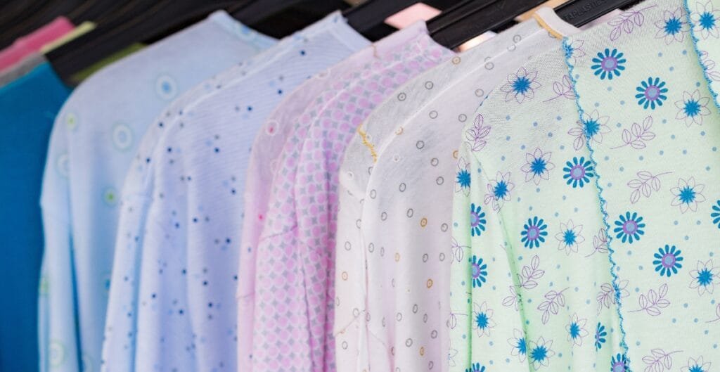 A row of colorful, patterned fabric or clothing items hanging on a rack, featuring various pastel colors and floral or dotted designs.