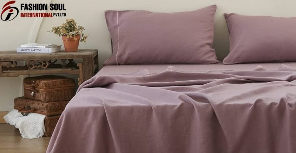 A cozy bedroom scene featuring a bed with mauve-colored bedspread and matching pillows, next to a rustic wooden nightstand with a small potted plant, a stack of books, and wicker baskets underneath, set against a light-colored wall.