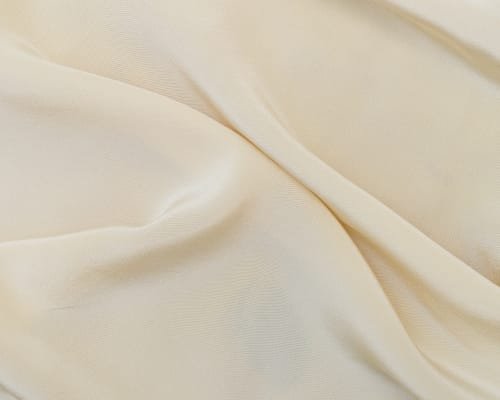 Close-up image of smooth, creamy-white plain cotton fabric with gentle folds.