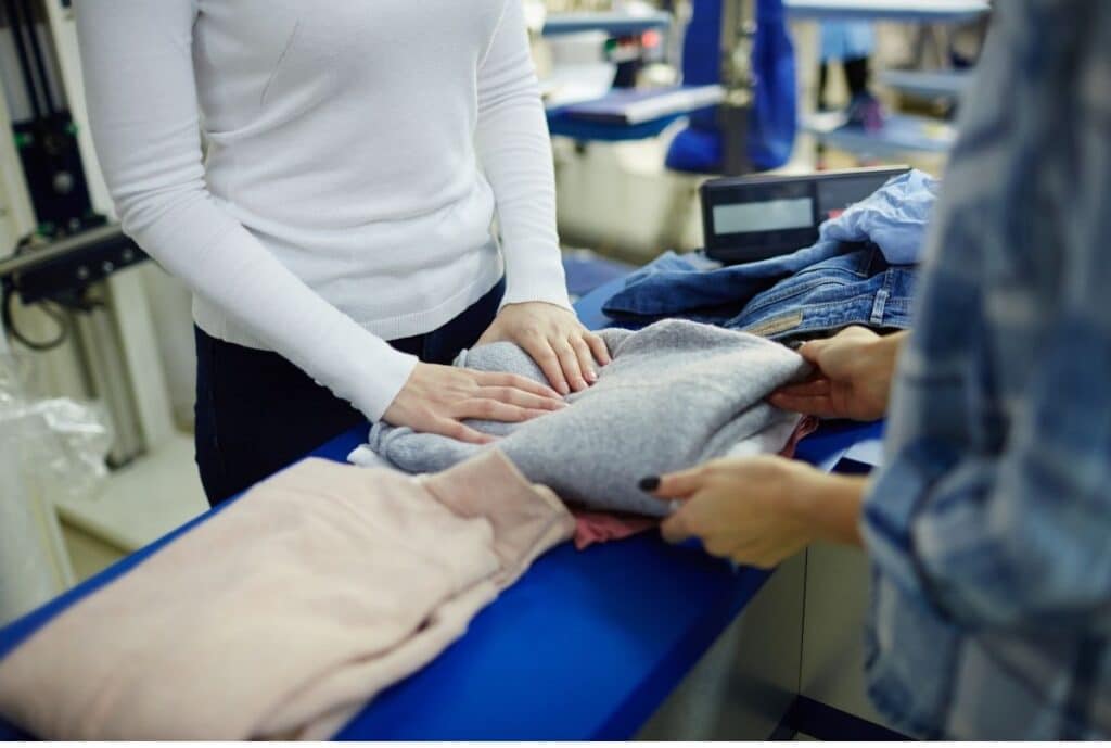 One man and a women doing quality Inspection of the clothes.
