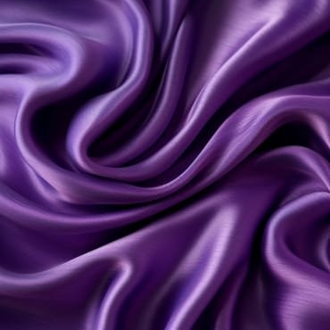 Close-up of shiny, purple polyester silk blend fabric with smooth, flowing folds.