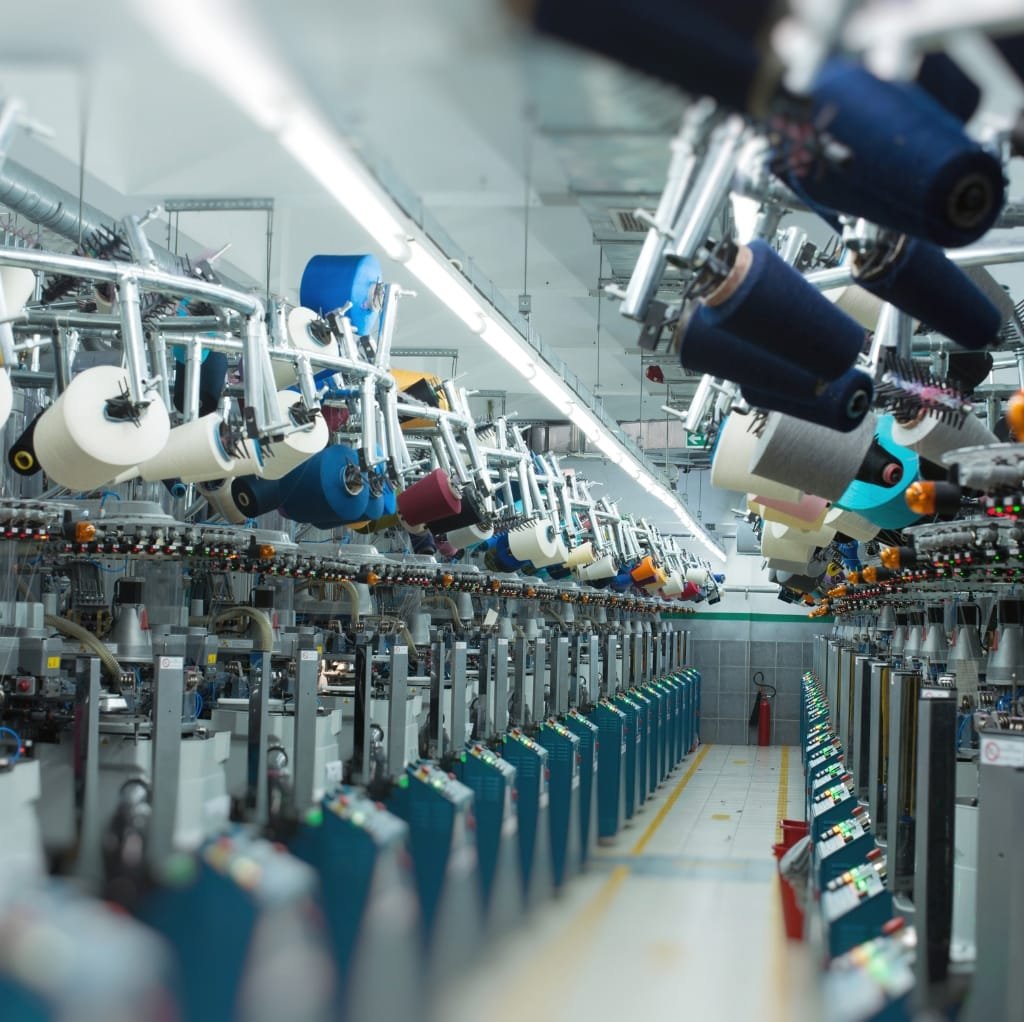 A modern textile manufacturing facility with multiple rows of automated machines producing fabric rolls, showcasing advanced technology in textile production.
