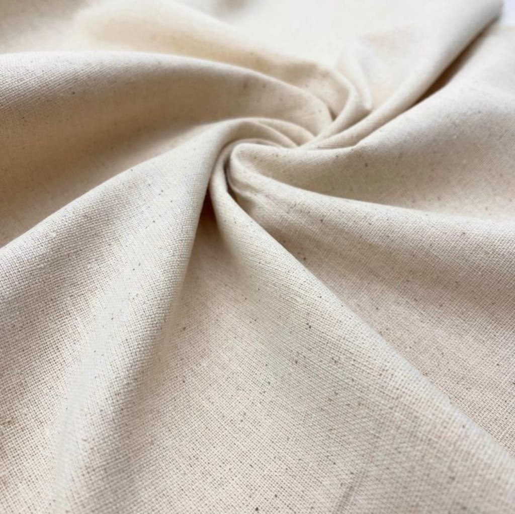 A close-up image of beige or natural-colored cotton fabric, gently twisted in the center, showcasing its soft texture and weave pattern.