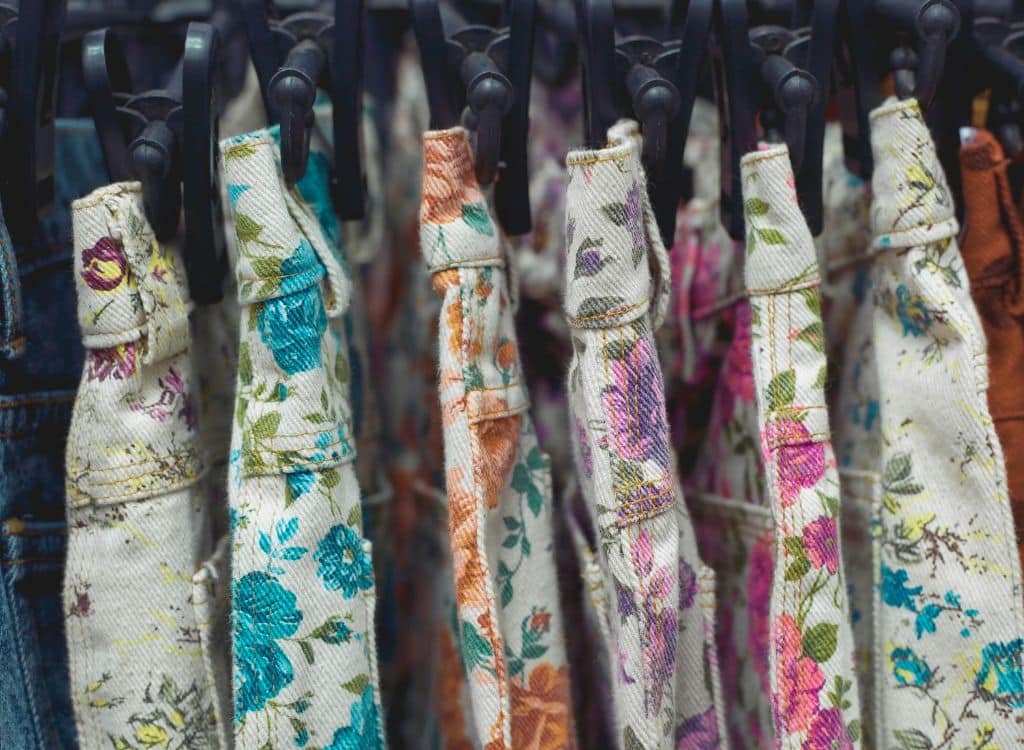 Close-up of floral-printed fabric masks hanging on a rack, showcasing vibrant designs.