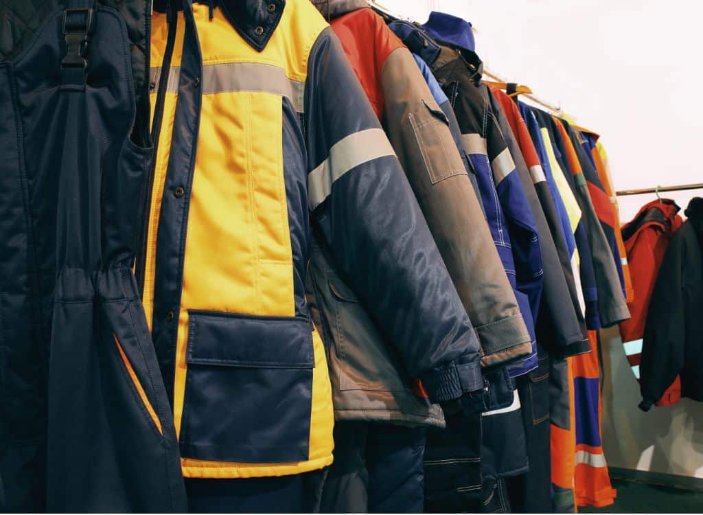 A row of various colorful work jackets hanging on a rack, representing clothing manufacturing.
