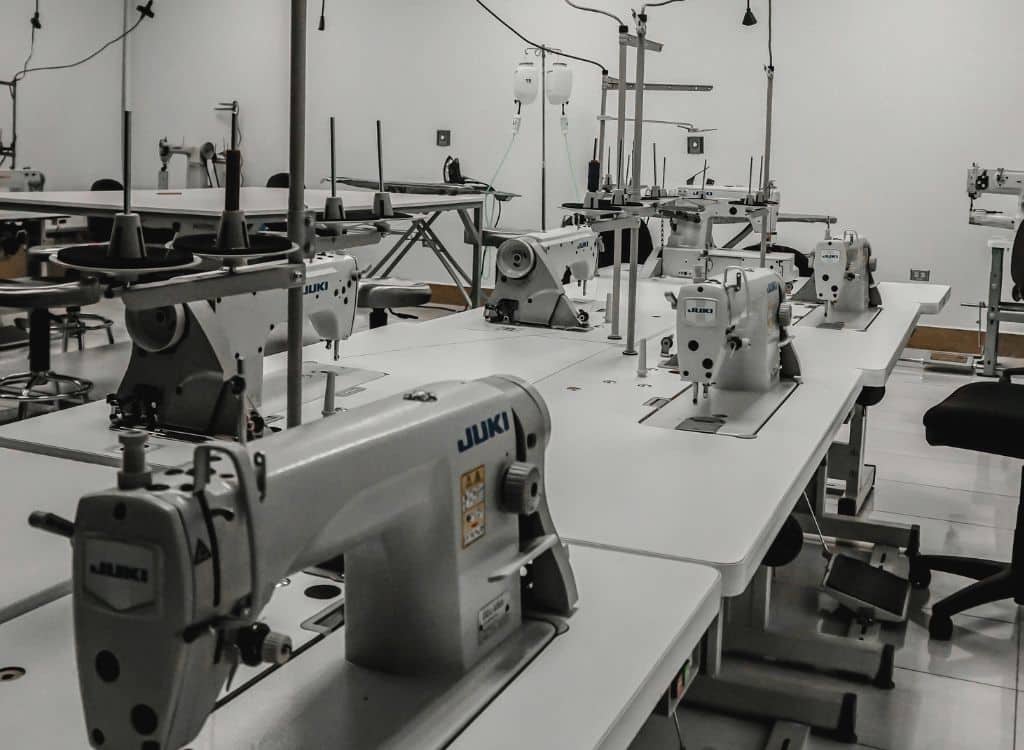 Modern sewing machines in a clean, well-lit production room at a clothing manufacturer in Rhode Island.