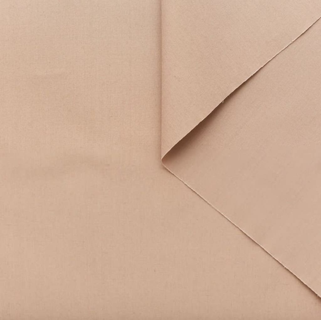 A close-up image of nude-colored poplin cotton fabric, with a folded corner revealing its smooth texture.