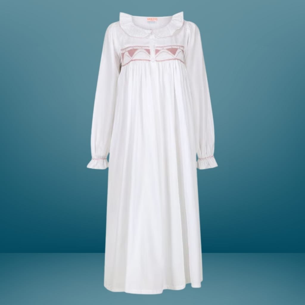 A long, white, embroidered nightgown or dress with long sleeves, ruffled cuffs, and a rounded collar, displayed against a blue background.