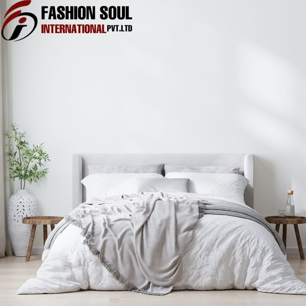 A minimalist bedroom with a white upholstered bed, neatly made with white and gray bedding. Two wooden side tables are positioned on either side of the bed, with decorative vases and a bottle on the right side. A small potted plant is placed on the left side, and a large abstract logo and text "FASHION SOUL INTERNATIONAL PVT. LTD" are displayed in the top left corner against a plain white wall.