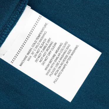 Care instruction label on a chambray fabric item, featuring washing and drying guidelines.